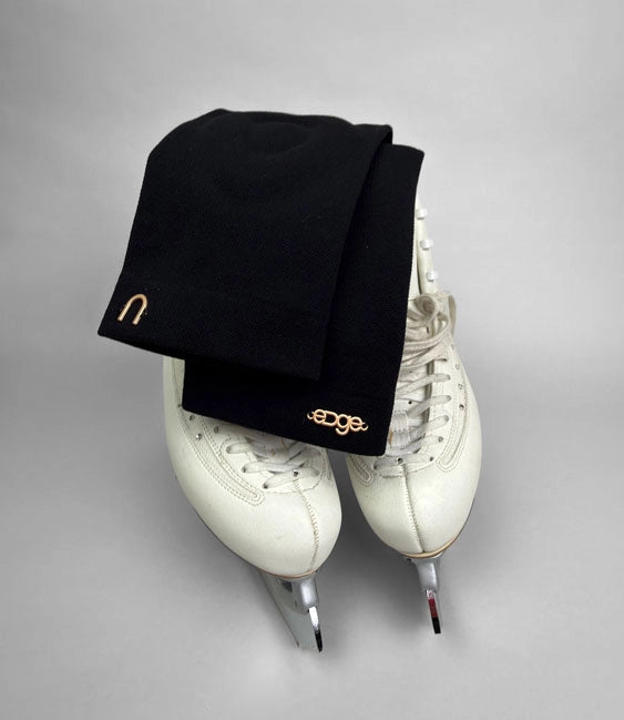 a pair of edge athletica black knee guards with white figure skates